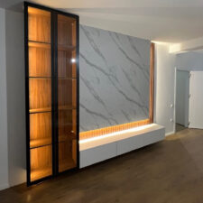 Διακοσμητικό πάνελ με ξύλινα πηχάκια πίσω από την τηλεόραση σε minimal εσωτερικό χώρο.